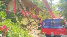 Kondisi belakang rumah Dewan Ariadi Gala yang tertimpa tiang listrik. Satu mobil truk Dyna merah dari PLN Rantepao sudah berada di lokasi dengan membawa tiang besi untuk mengantikan tiang listrik yang tumbang. Foto Dok:(Erlinuddin/inspirasipos.com).                 