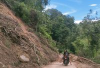 Material longsor yang menutup sebagian jalan di Lembang Rante, Jumat (18/04/2025) sore. Nampak pengendara sepeda motor berhati hati melewati jalan tersebut. Foto Dok: Moh Fadhli Wahab/inspirasipos.com.